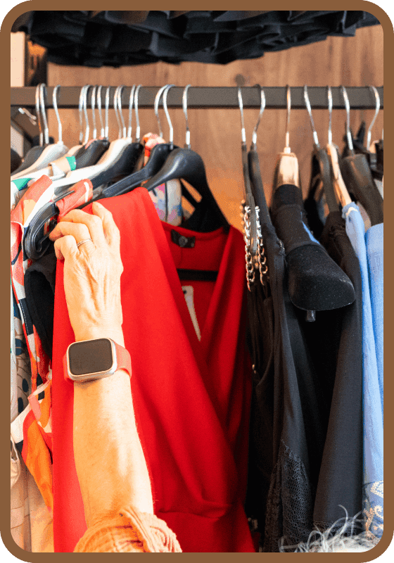 Woman selecting red dress from clothing rack.
